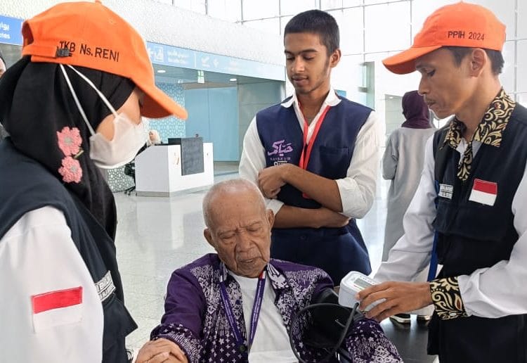Petugas kesehatan memeriksa suhu tubuh jemaah haji yang baru tiba di bandara sebagai langkah deteksi dini penyebaran Covid-19.